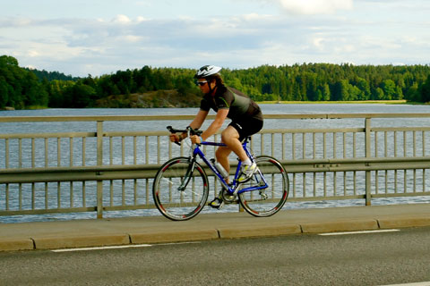 photograph of chris southwell cycling on a road with lake and trees in the background